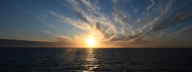 Image of a sunrise over the ocean with clouds above