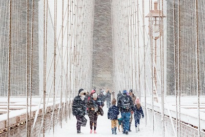 People walking across Brooklyn Bridge in a blizzard