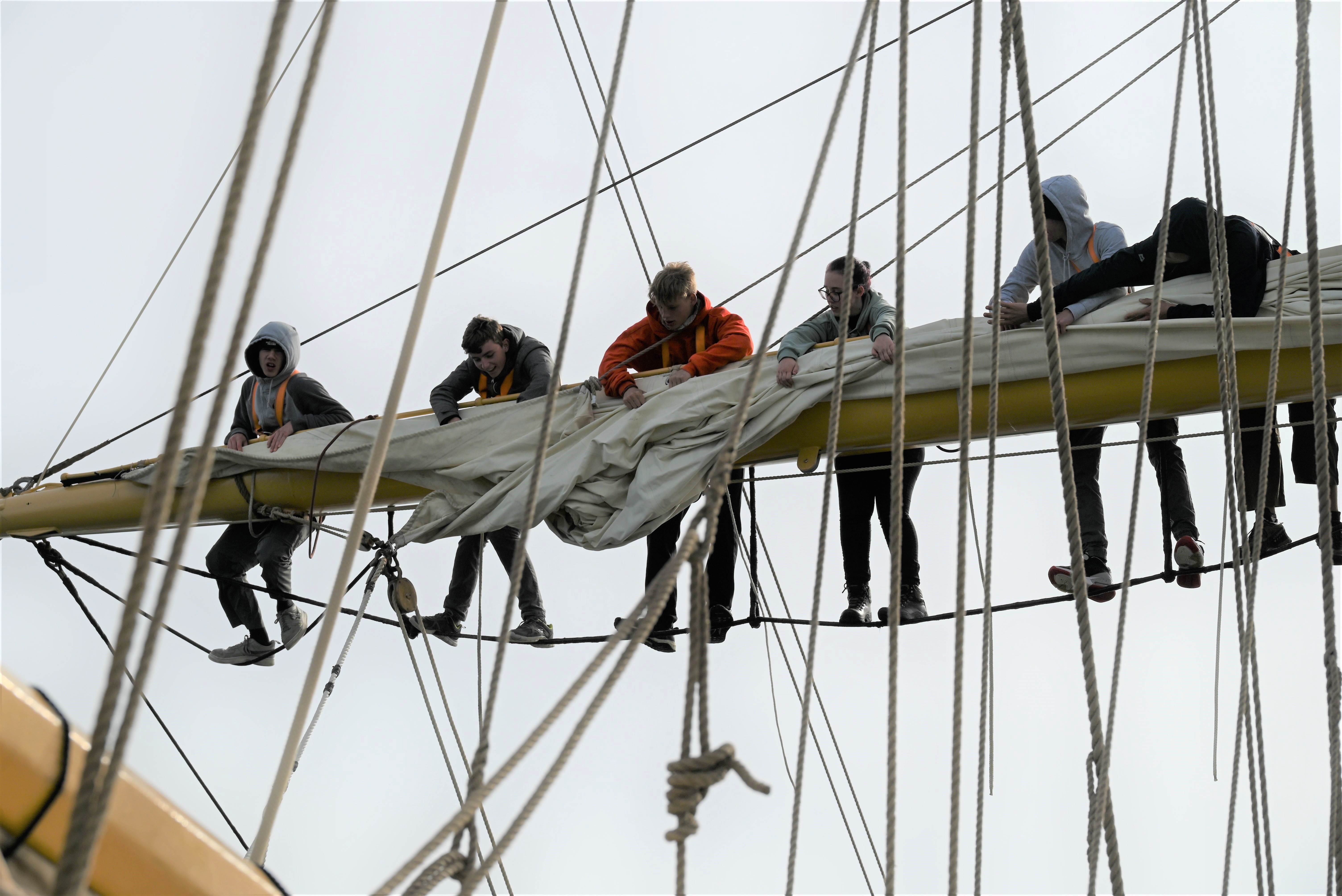 Trainees on the yard of the Pelican of London, stowing sails