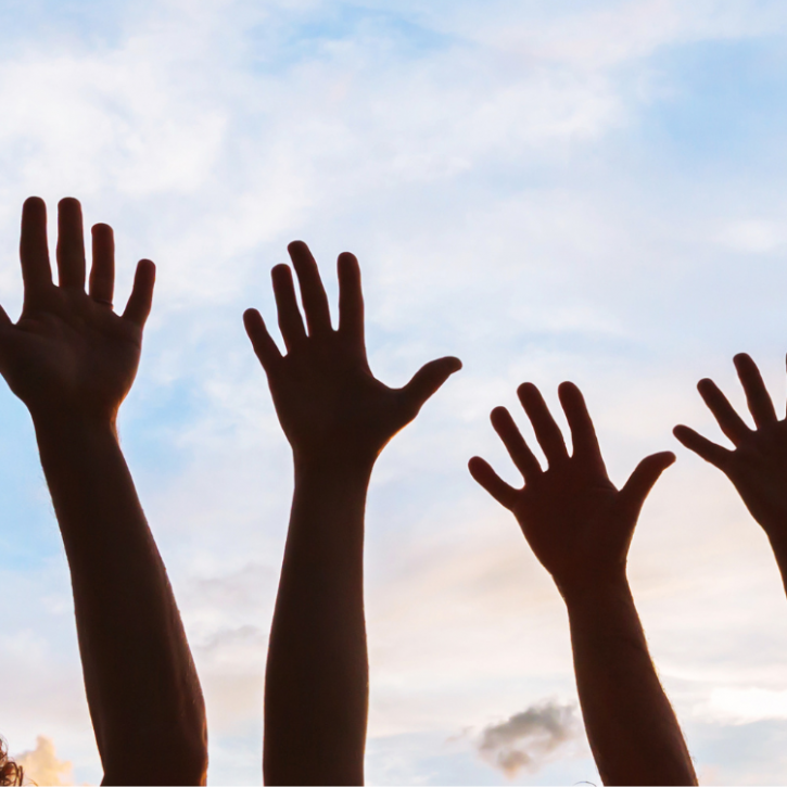 silhouette of hands in the air in front of a blue sky 