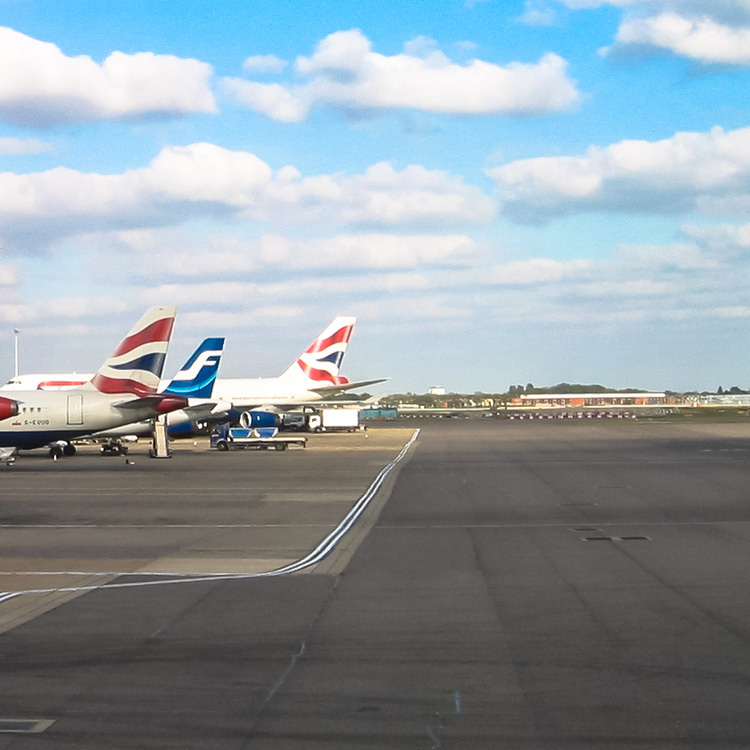 plane tails on runway at Heathrow with blue sky and clouds
