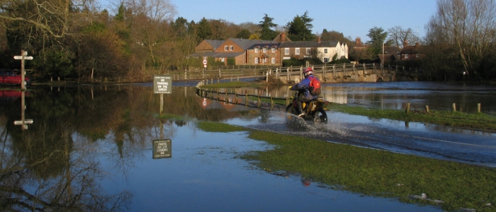 motorcyclist driving through a flooded road in the UK