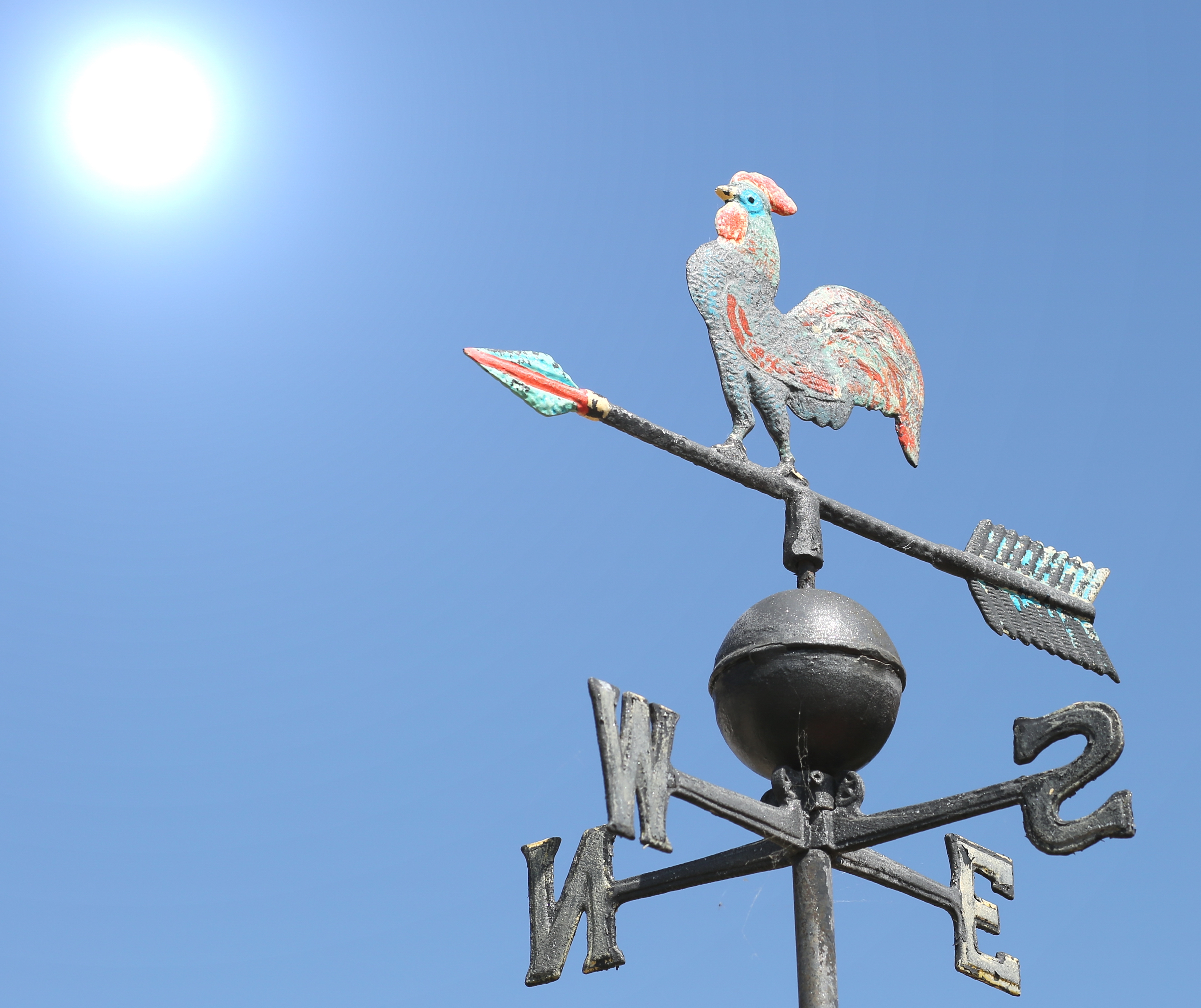 Weather vane against blue sky