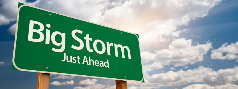 Green sign with the words big storm just ahead written on it, in front of a blue sky