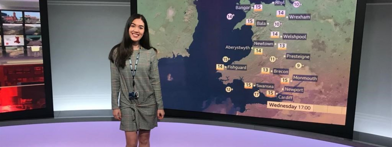 Image of a weather woman standing in front of a map of Wales showing the weather