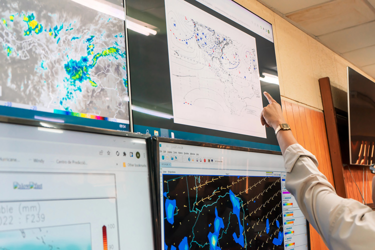 A meteorologist points at a weather chart
