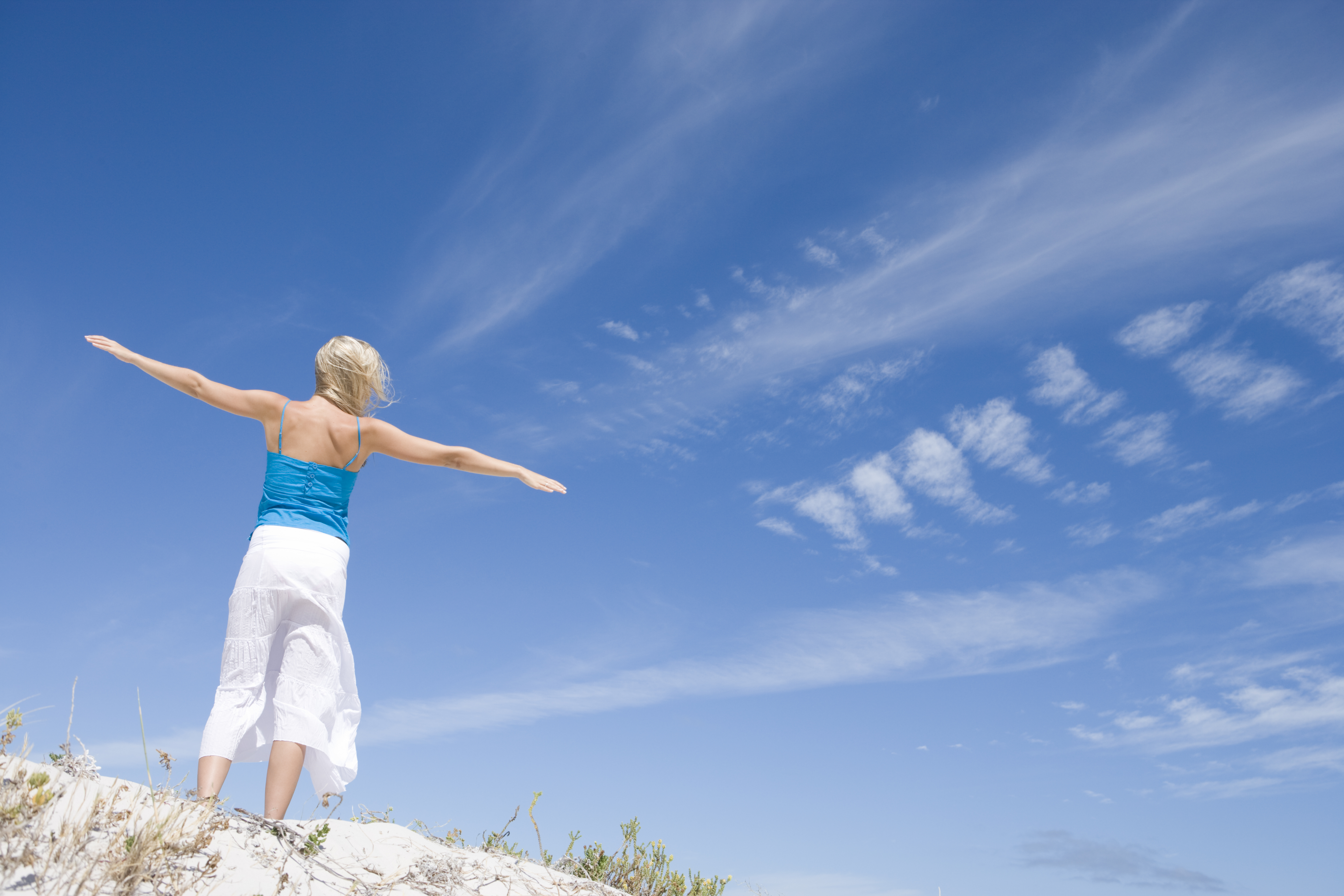 Person holding their arms out looking at blue skies