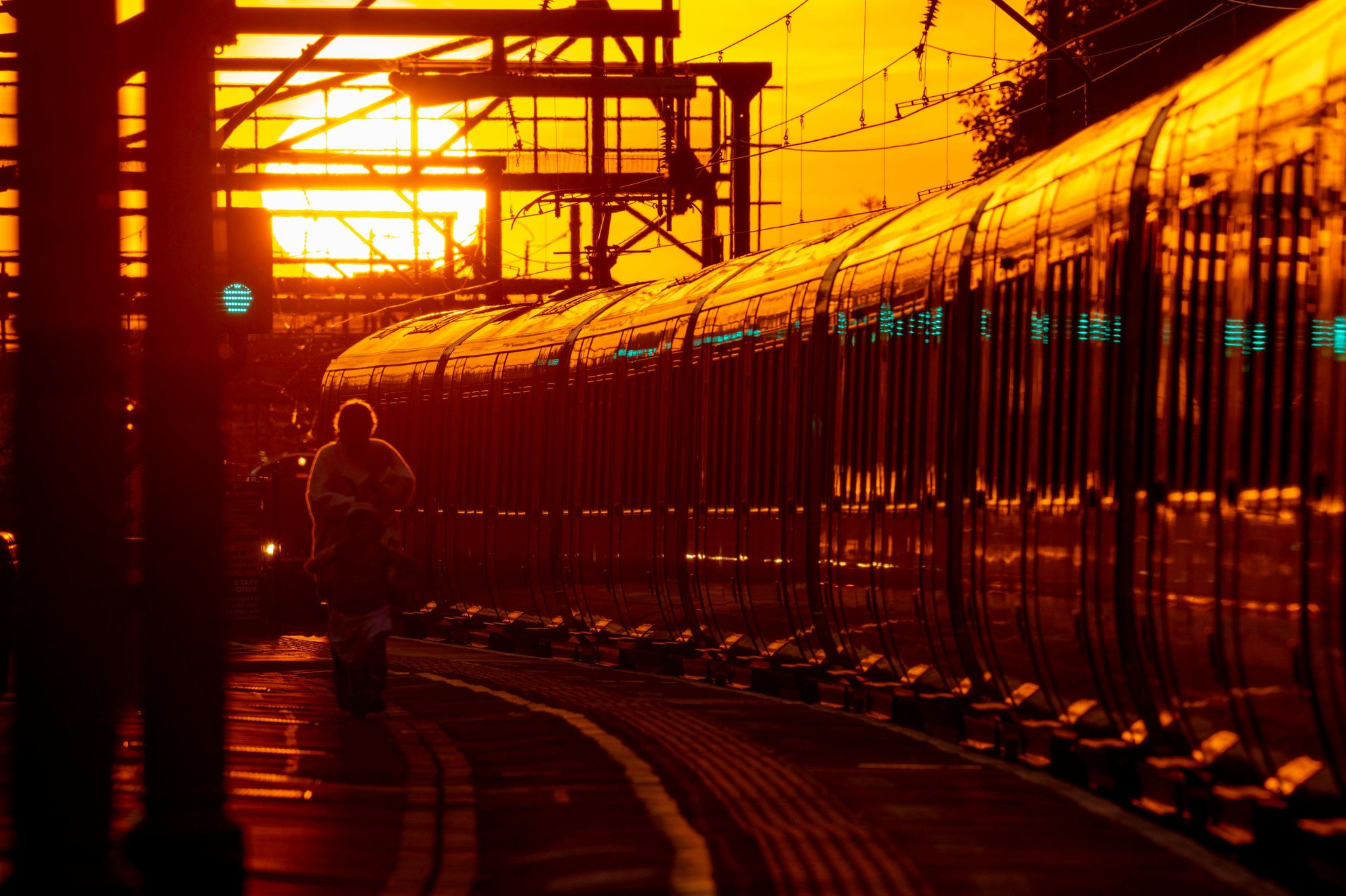 Train at station bathed in deep orange sunset