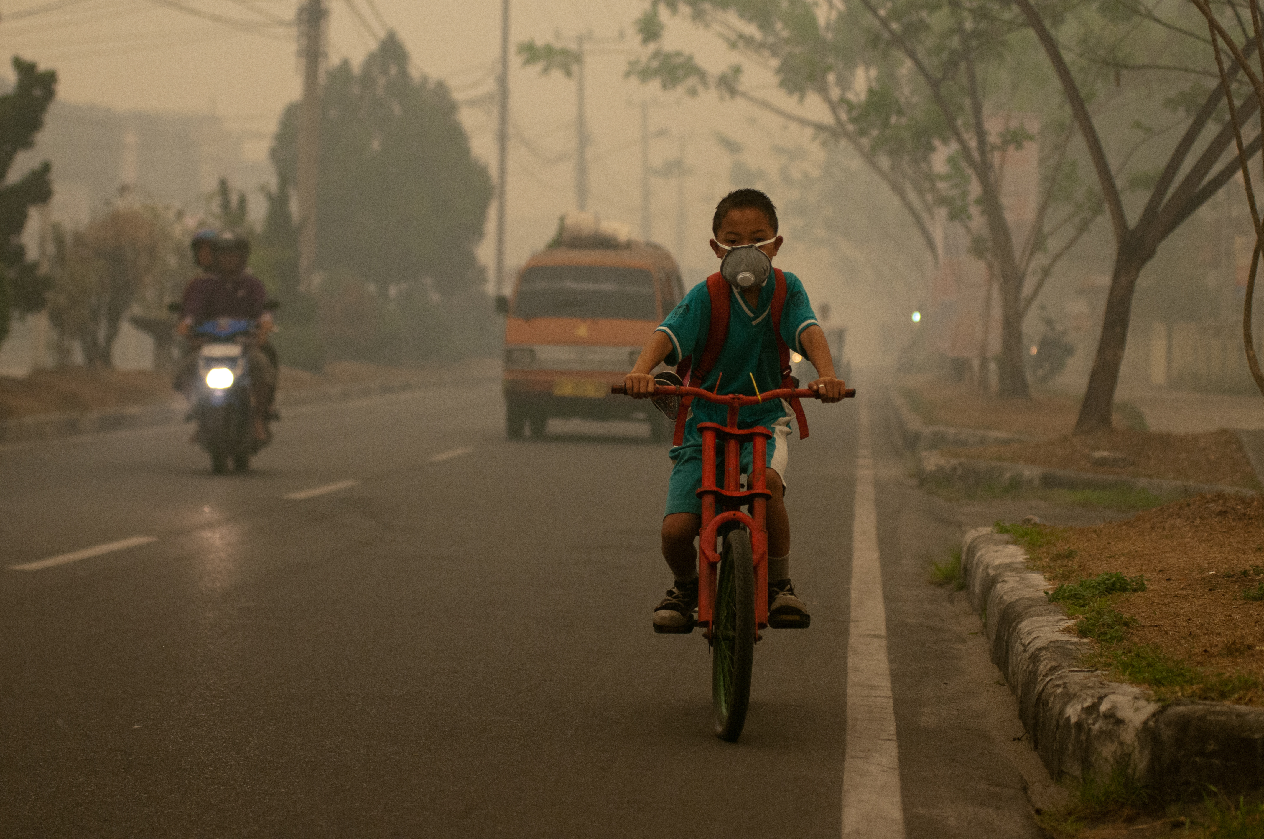 Boy cycling through smoke with a mask