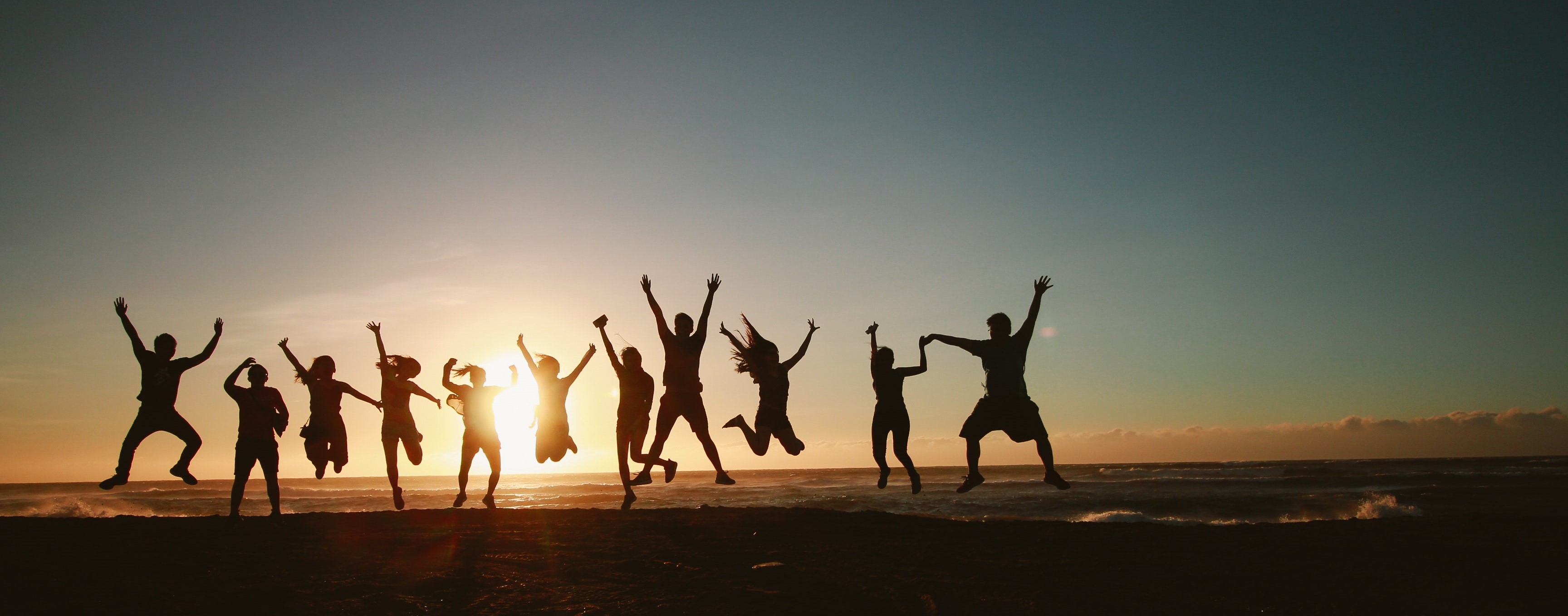 Silhouette of people jumping for joy against a sunrise