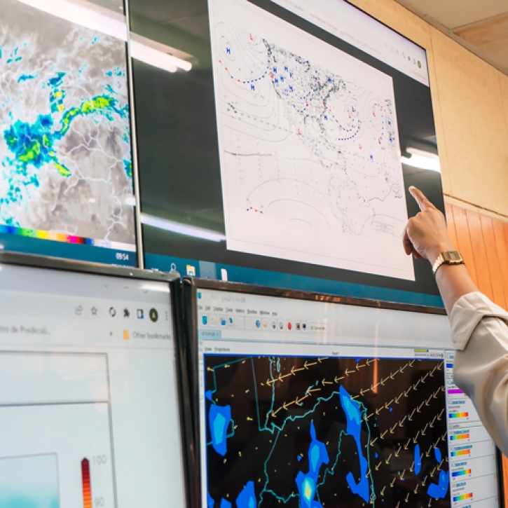 A meteorologist points at a weather chart
