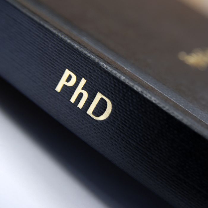 A black book with "PhD" written on the spine