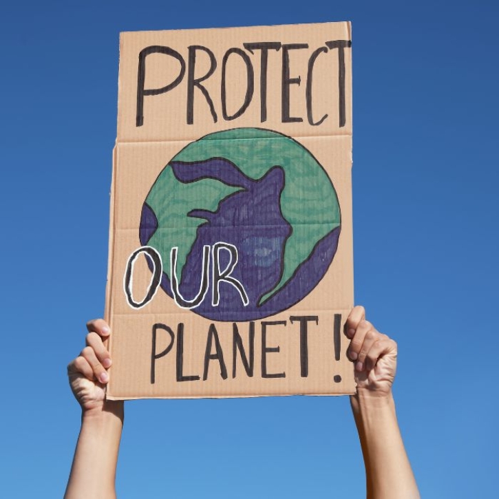 A person holding a sign that says, "Protect our planet!"