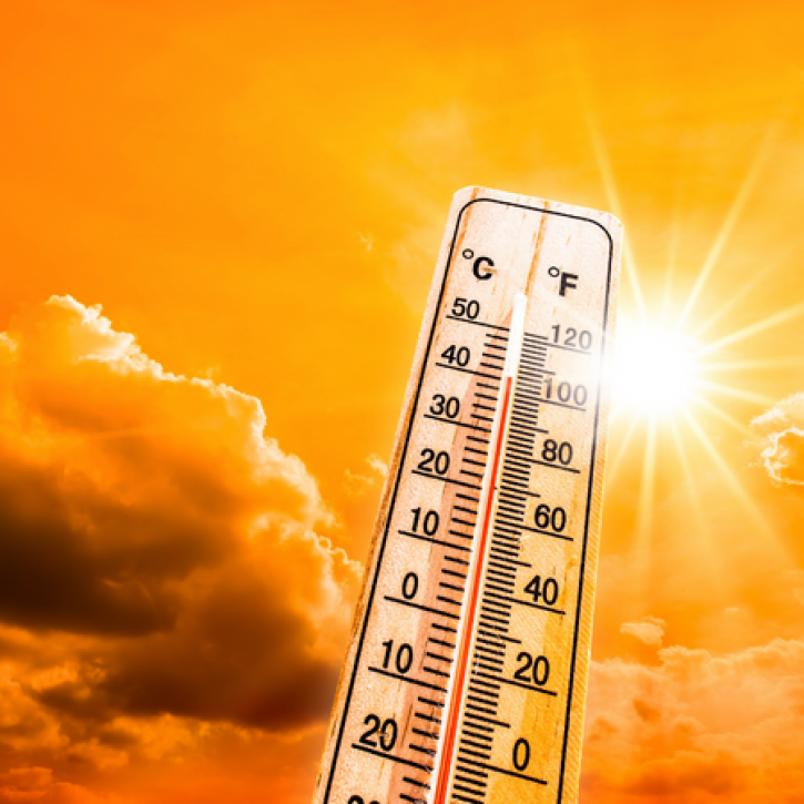 Image of a thermometer in front of an orange sky with sun 