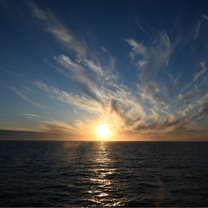Image of a sunrise over the ocean with clouds above